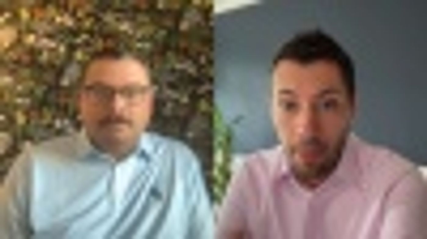 Two men in a video call, one wearing a blue shirt and the other a pink shirt.