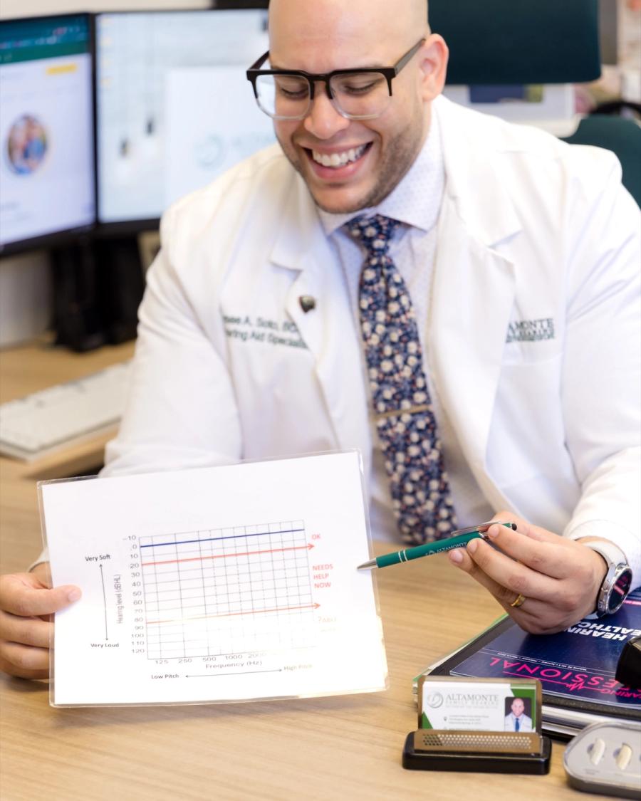 Jaysee laughing while explaining an audiogram at his desk