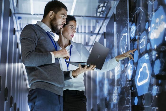 two people, one holding a laptop, examining a infographic