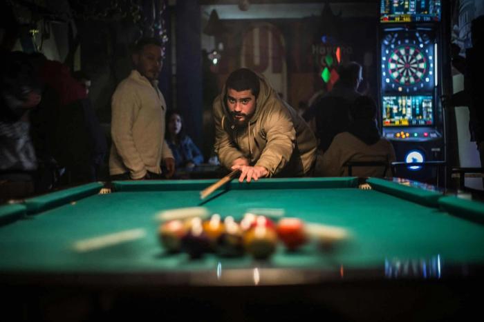 Person breaking off a game of pool in a bar setting