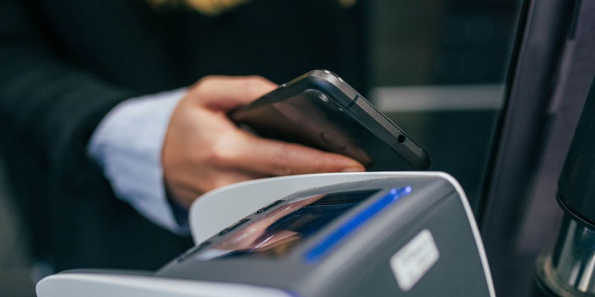 person holding a mobile phone near a payment terminal