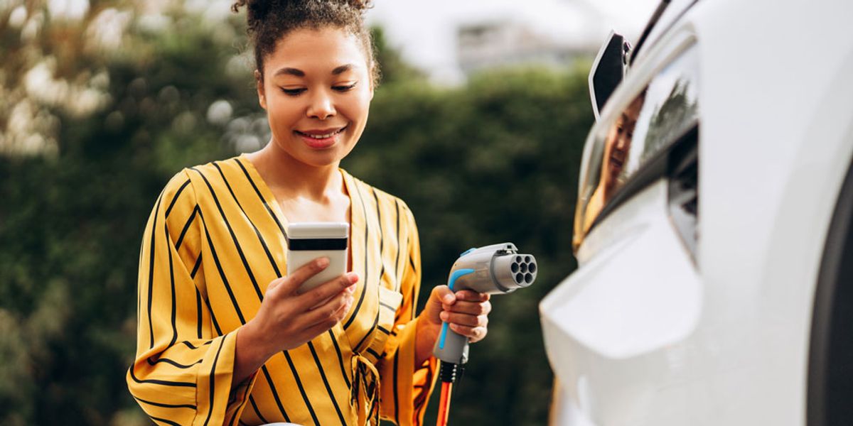 Person looking at their phone while plugging in their electric vehicle