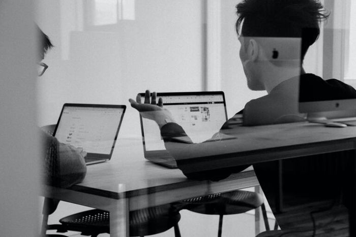 Two people in active discussion around their laptops