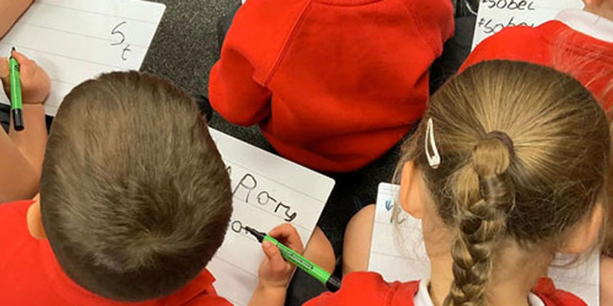 Schoolchildren sat on the floor writing
