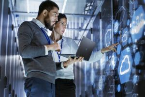 two people, one holding a laptop, looking at an infographic on the wall