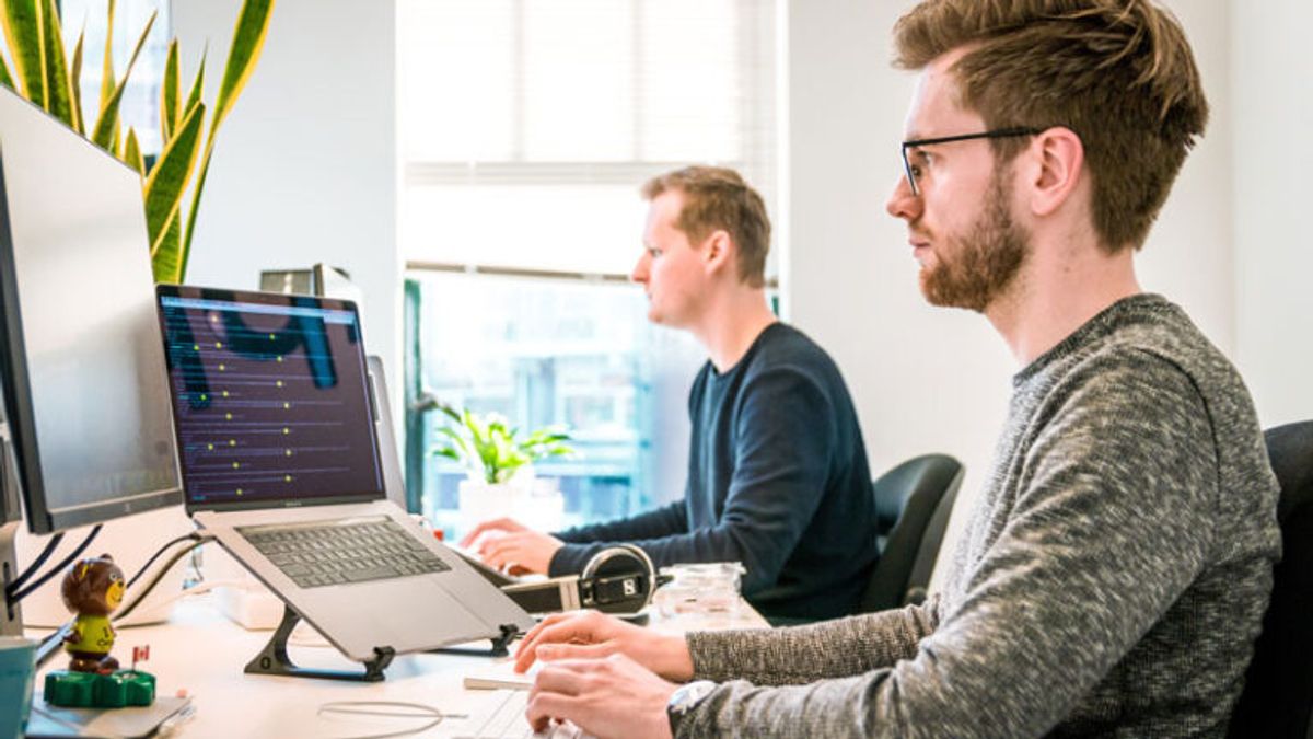 Two people sat at a desk coding