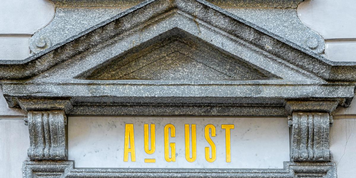 The top of a building entrance with the word August on it
