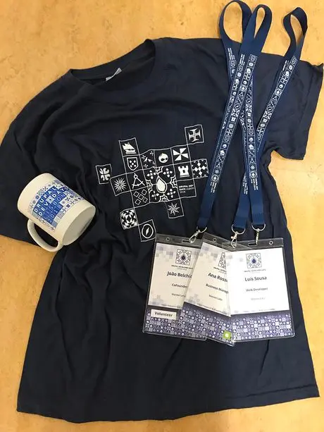 Swag from Drupal Dev Days Lisbon 2018: a t-shirt, mug and three conference badges
