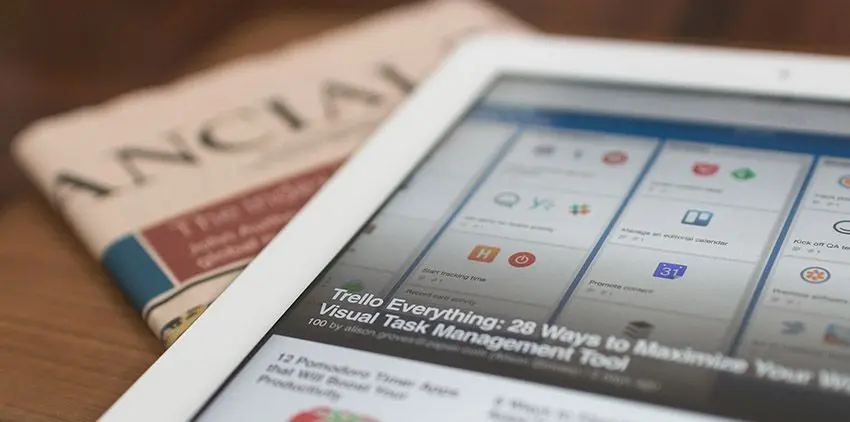 tablet showing an article about Trello with a journal behind it