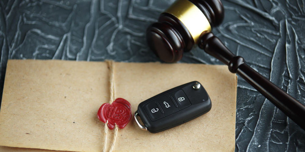 Chave de carro sobre documento com lacre e martelo de juiz ao fundo, representando leilão de veículos, regularização e aspectos legais na compra de carro usado
