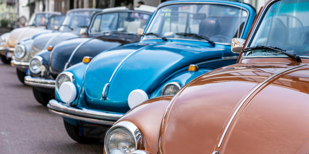 Fila de carros clássicos Volkswagen Fusca coloridos estacionados, representando veículos antigos, colecionismo automotivo e carros vintage