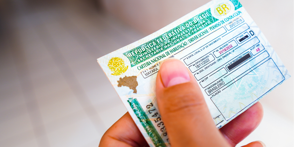 Pessoa segurando uma Carteira Nacional de Habilitação (CNH) brasileira, documento obrigatório para conduzir veículos no Brasil