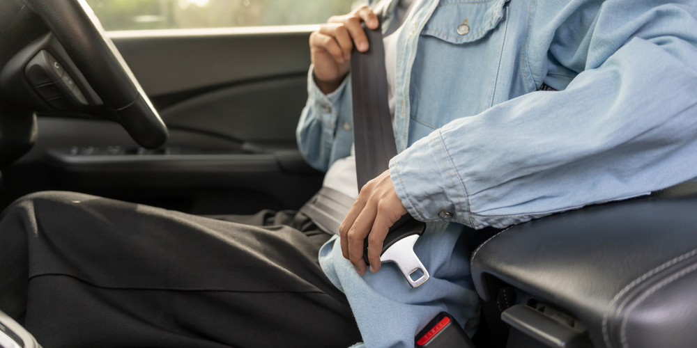 Motorista afivelando o cinto de segurança antes de iniciar a viagem, simbolizando práticas de direção preventiva e segurança automotiva