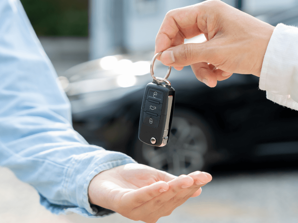 Mão de uma pessoa entregando chave de carro para outra