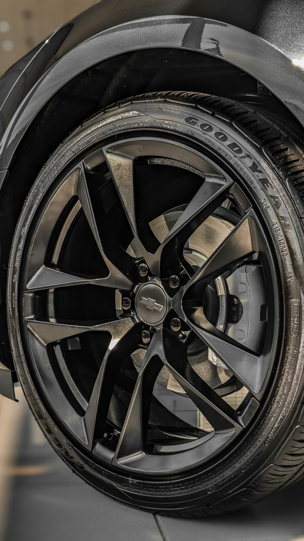 Detalhe lateral de roda esportiva Chevrolet aro 20 com acabamento em preto acetinado, destacando o sistema de freios a disco e pneus de alta performance