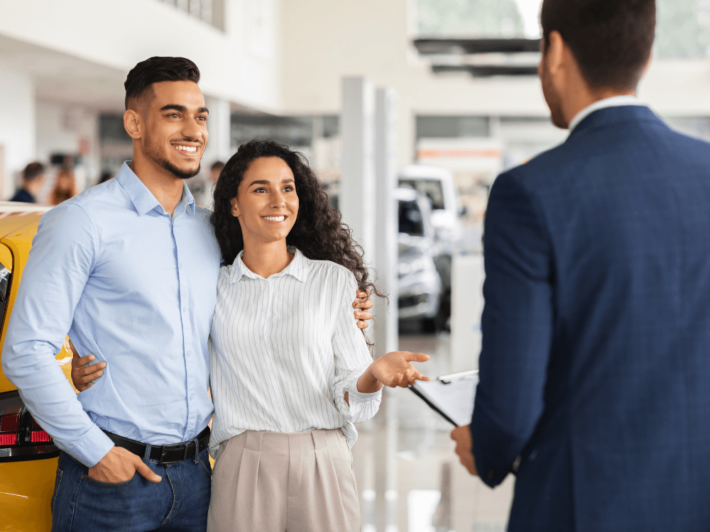 Casal conversando com vendedor em uma loja de carros