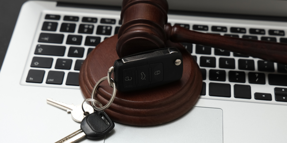 Martelo de leilão e chave de carro sobre notebook representando leilão online de veículos e compra segura de automóveis