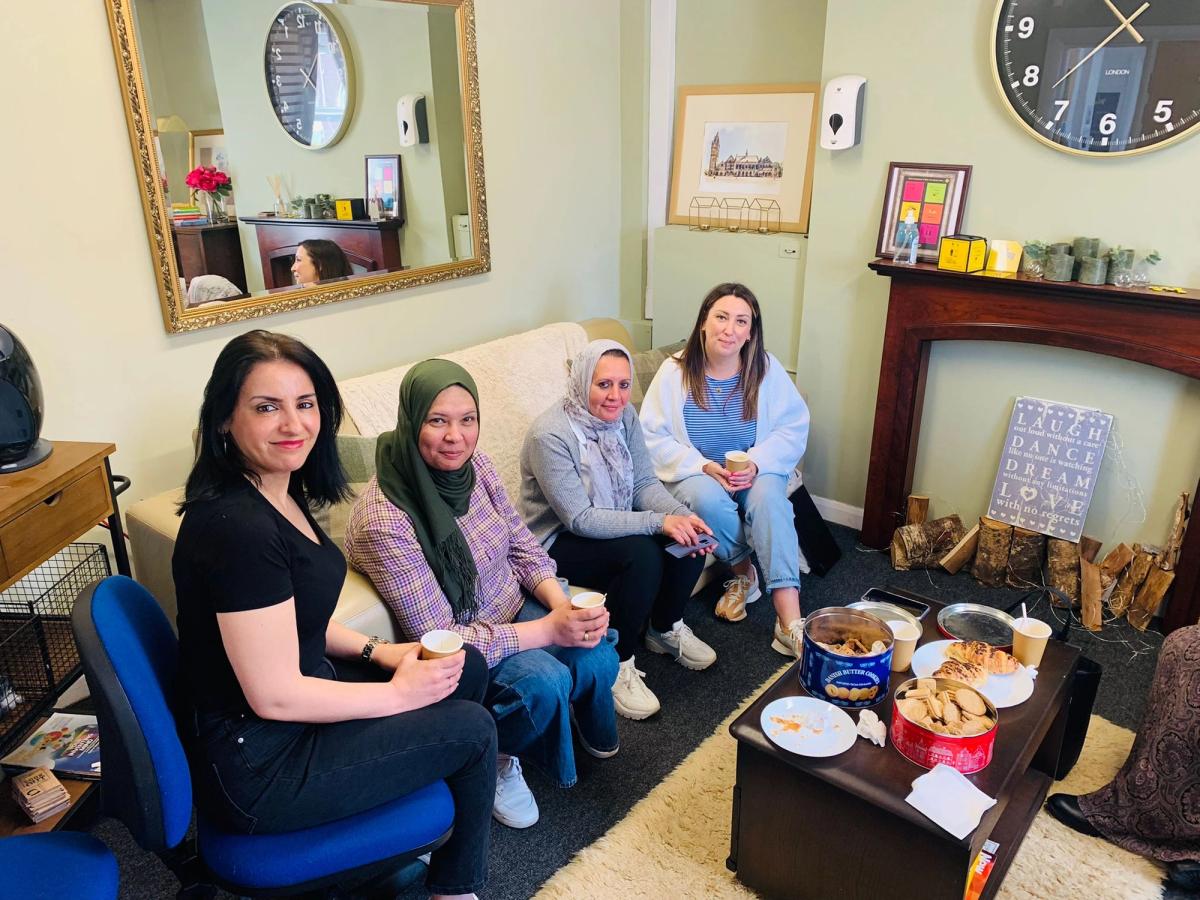 four women sat in a living room having tea