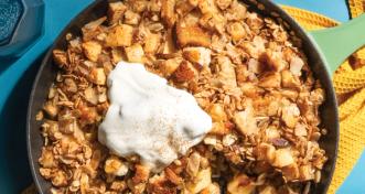 apple crisp in cast iron pan on blue table with yellow napkin