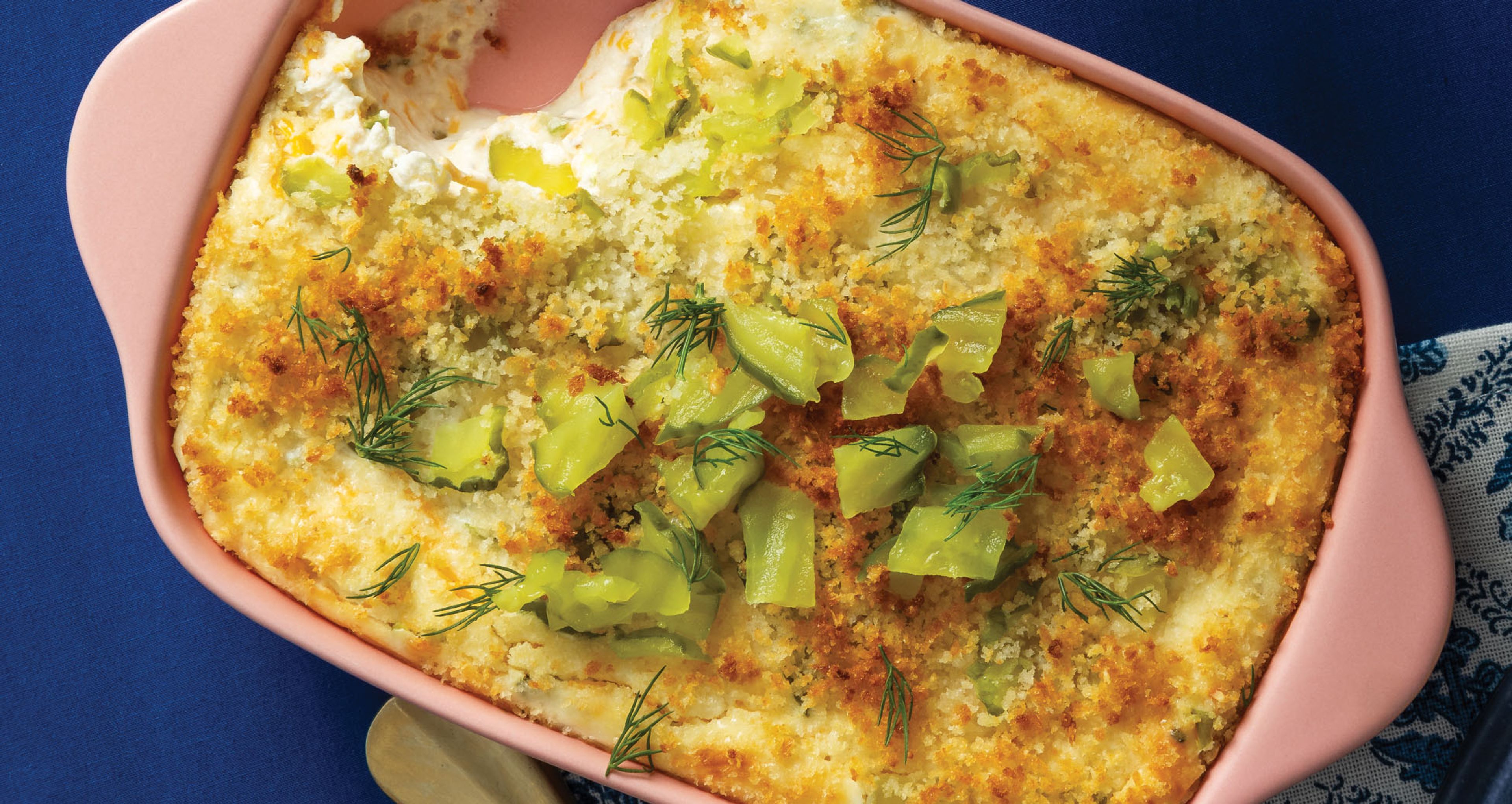 baked dip with pickle garnish in pink pan