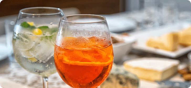 Two cocktails and cheese blocks in the background