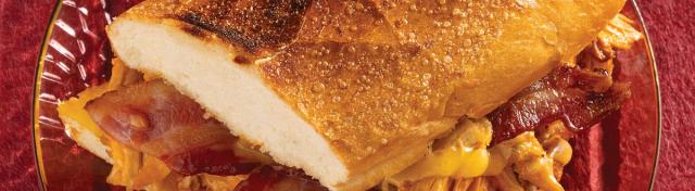 A warm, toasted chicken bacon ranch sub sandwich cut in half on a clear glass plate.