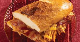 A warm, toasted chicken bacon ranch sub sandwich cut in half on a clear glass plate.