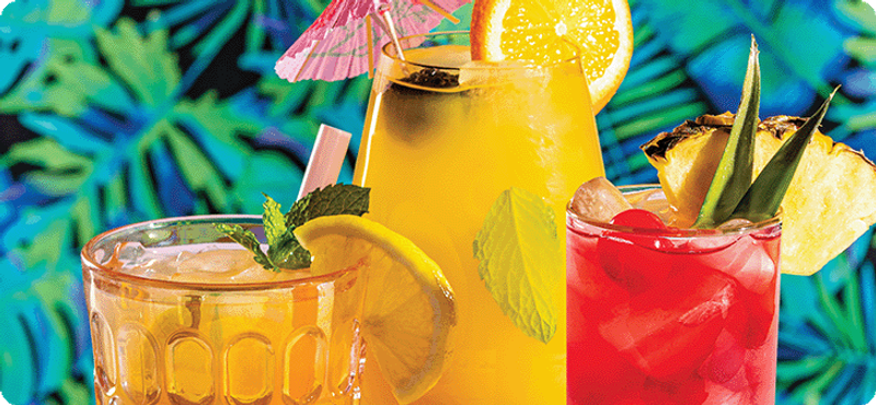 Three tiki cocktails with fruit garnish on glass