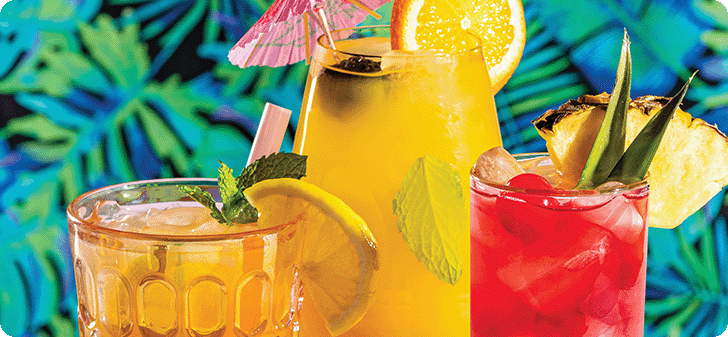 Three tiki cocktails with fruit garnish on glass