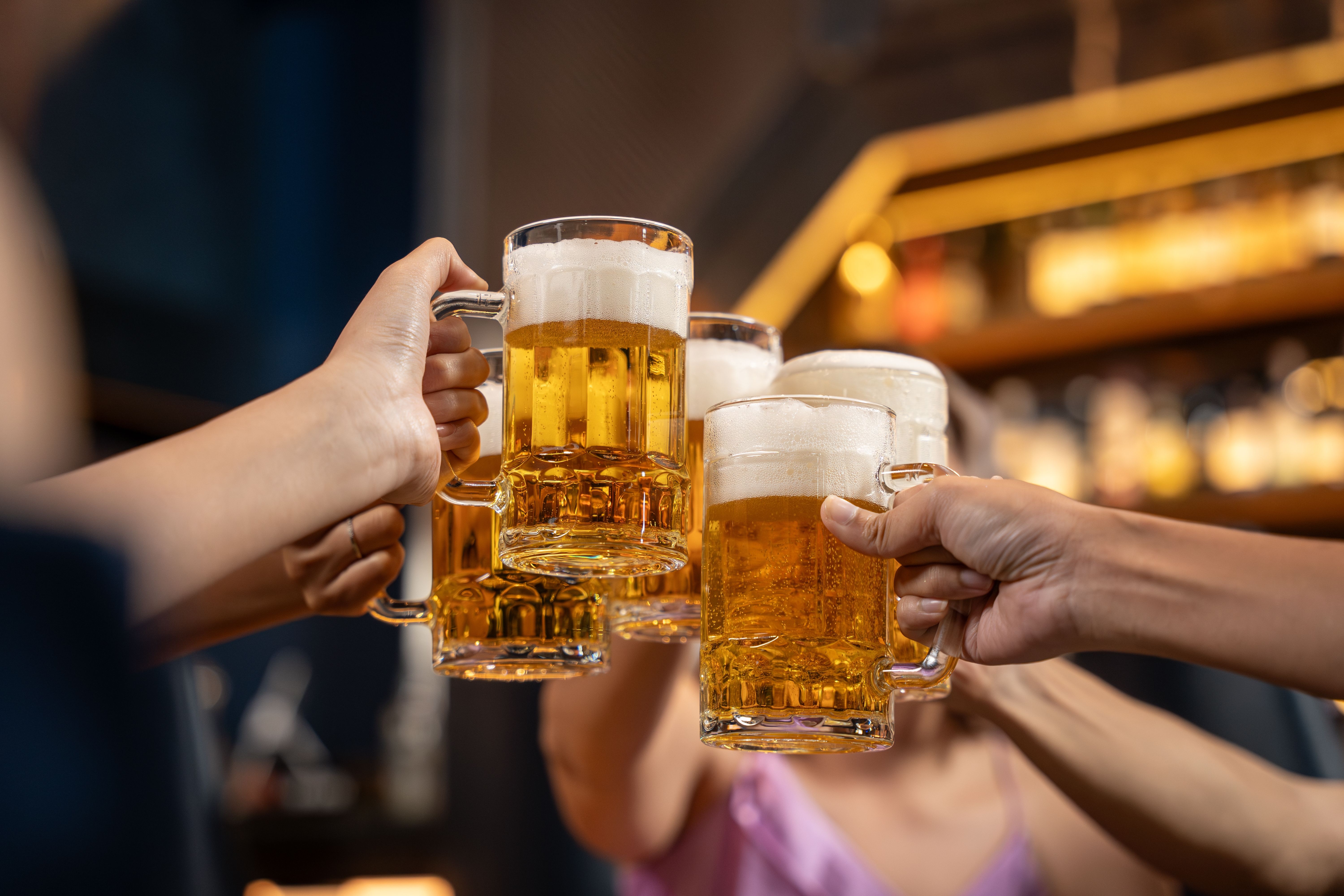 Group of people holding beer and cheer in restaurant