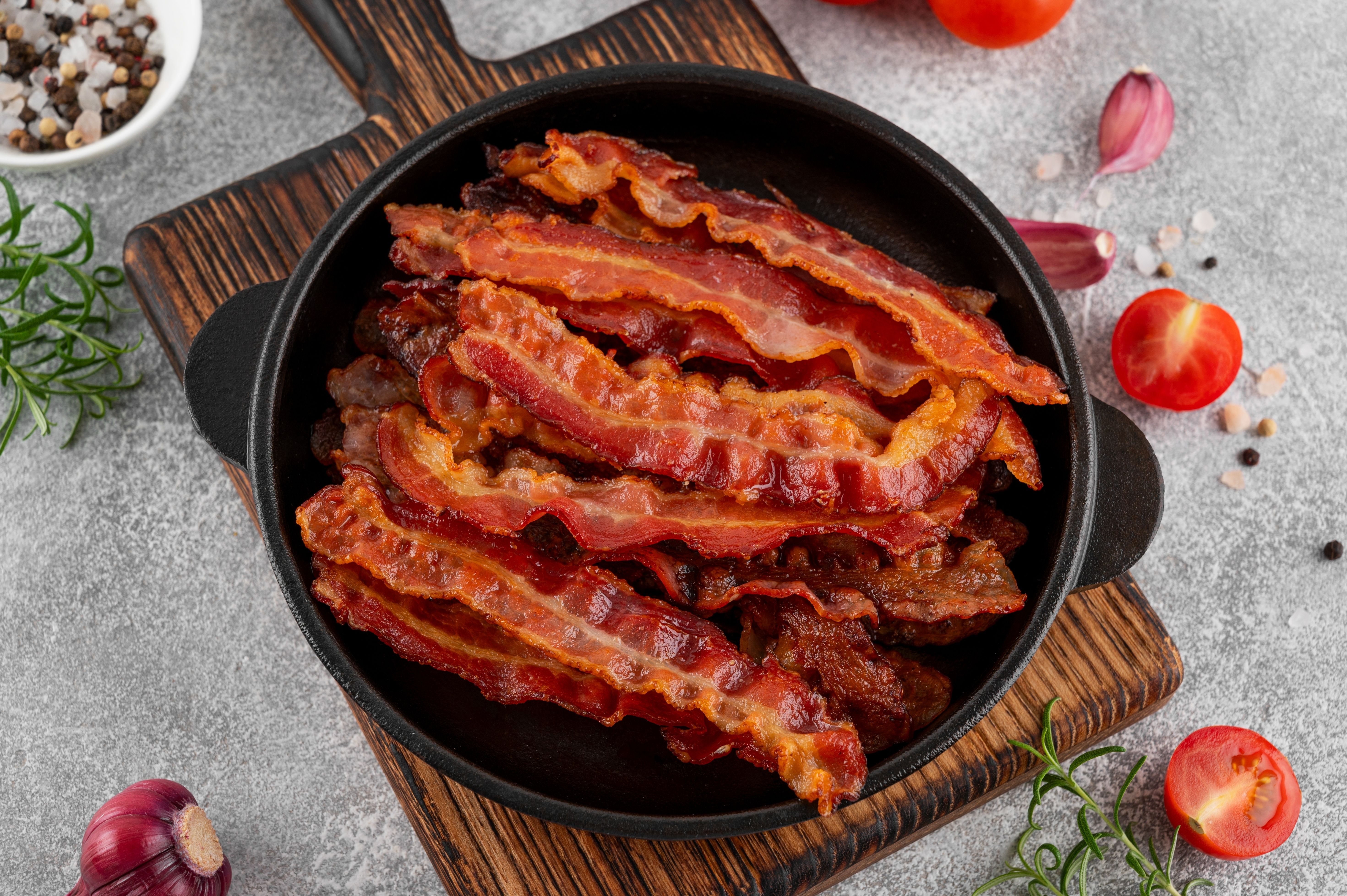 Fried slices of bacon for breakfast in a cast iron pan