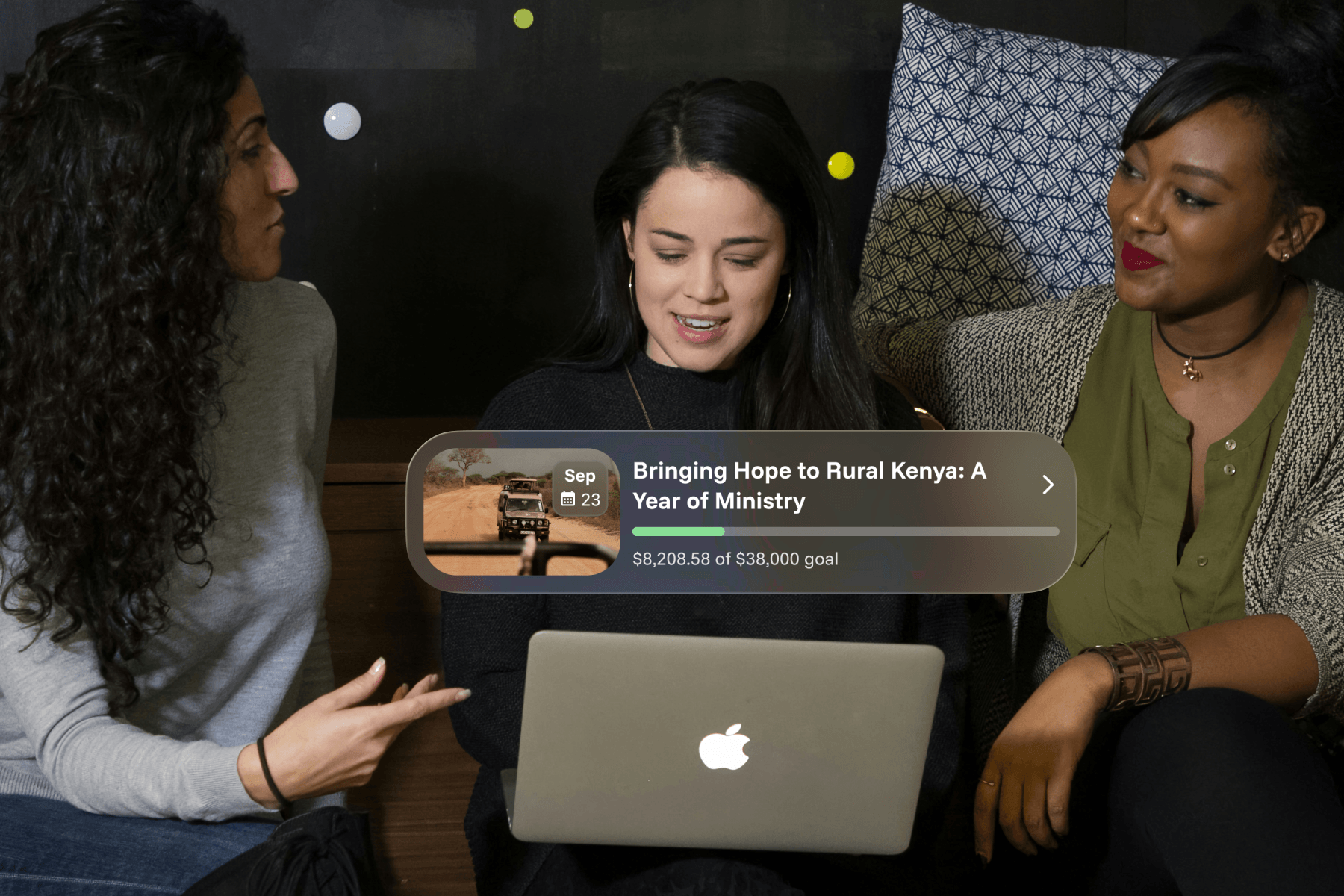 Three women looking at a MacBook together, with a Sowfund fundraiser card showing "Bringing Hope to Rural Kenya: A Year of Ministry" at $8,208.58 of a $38,000 goal.