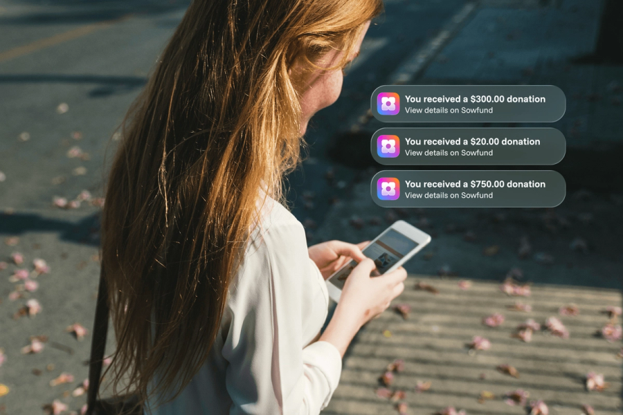 A woman with long red hair looking at her phone outdoors, with three Sowfund donation notifications showing received amounts of $300.00, $20.00, and $750.00.