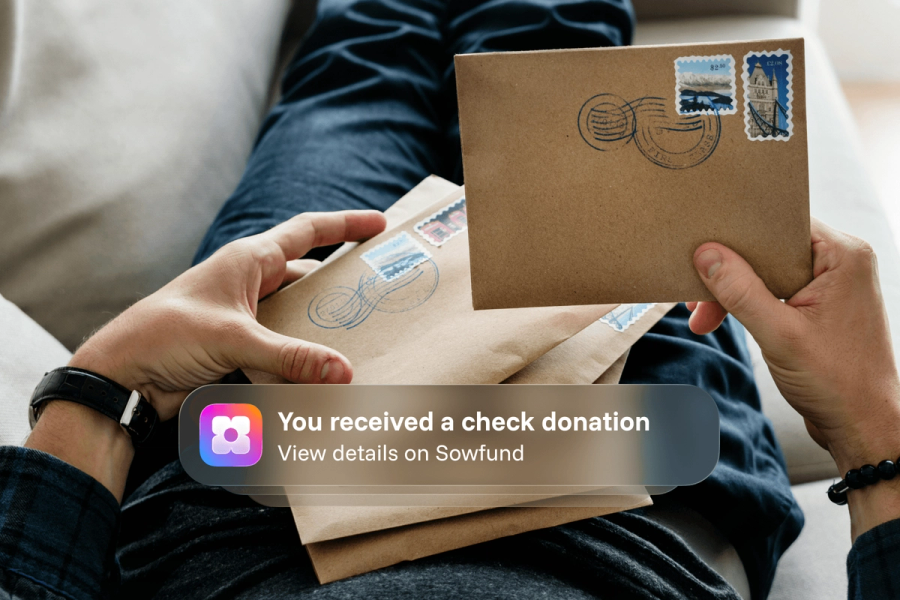 A person holding stamped mail envelopes, overlaid with a Sowfund app notification: "You received a check donation — View details on Sowfund."