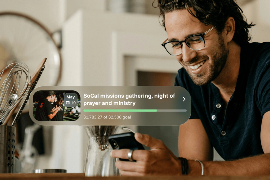 A smiling man looking at his phone in a kitchen, with a Sowfund fundraiser card overlaid showing "SoCal missions gathering, night of prayer and ministry" at $1,783.27 of a $2,500 goal with a green progress bar and a May 19 event date