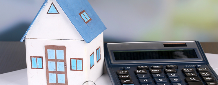 A calculator and a pair of keys next to a small white and blue model of a house