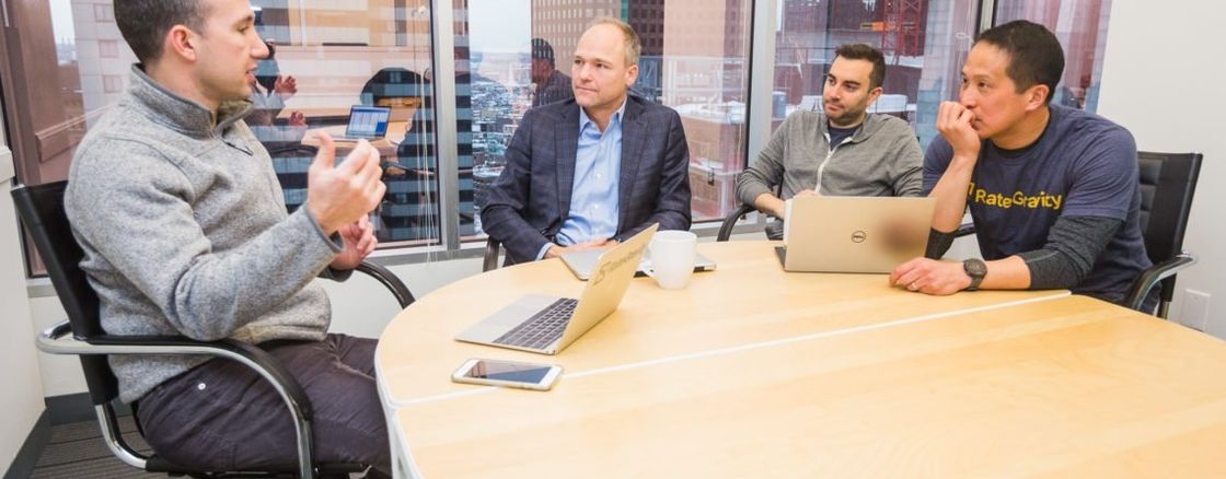 Four gentlemen sitting around a conference table talking