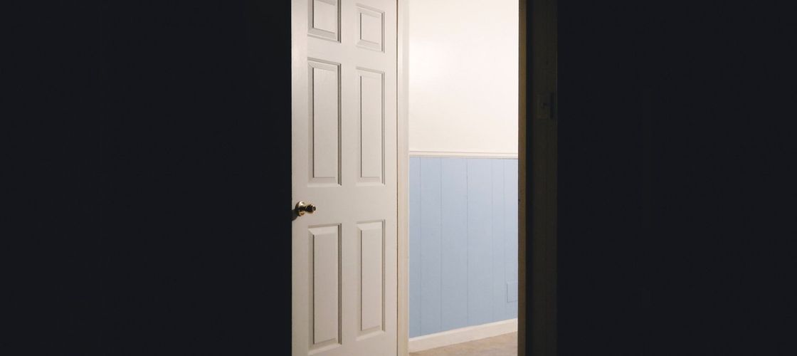 A dark room with a door opening into a lit hallway