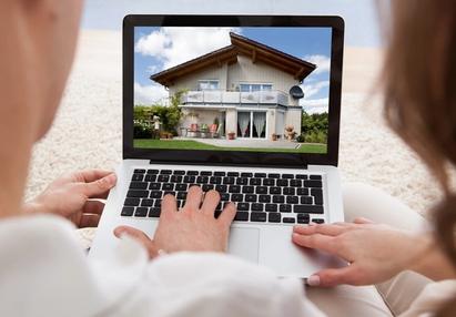 Two people looking at houses on a laptop