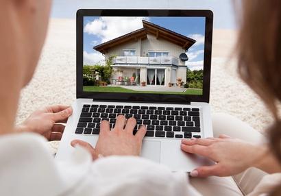 Two people looking at houses on a laptop
