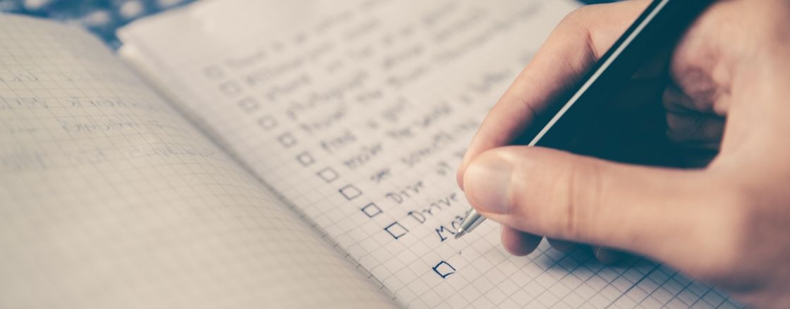 Person filling out a checklist on a notebook
