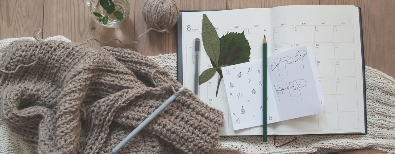 a table with a calendar planner and a sweater on top