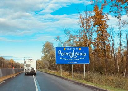 Welcome to Pennsylvania road sign next to the highway on a fall day