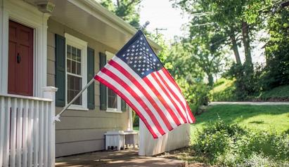 House with large porch and American flag. 