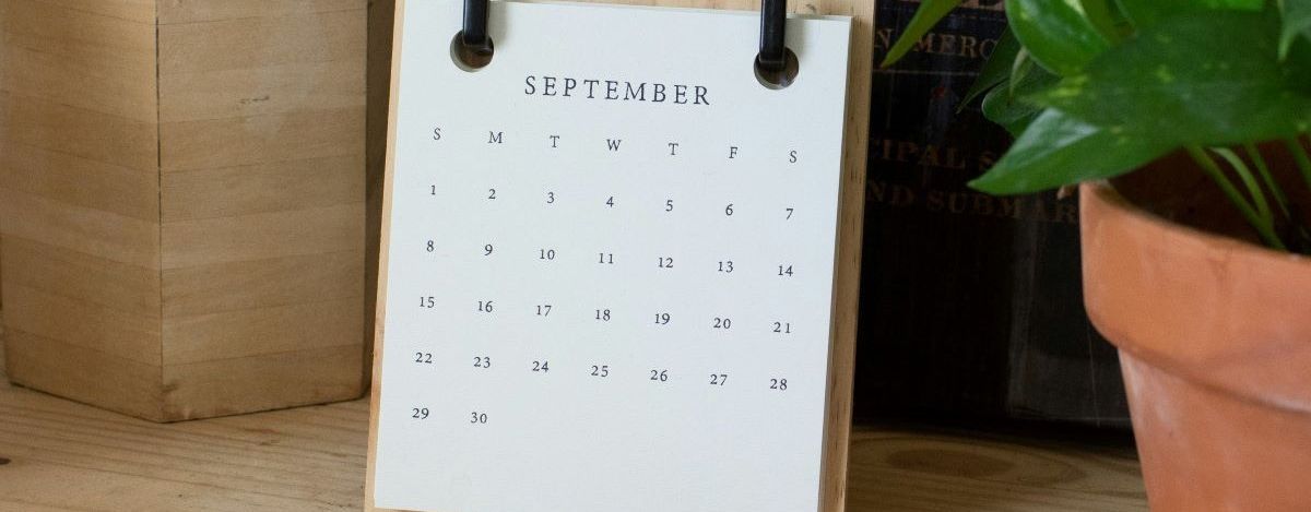 A calendar for the month of September on a desk next to a plant; photo by Blessing Ri on Unsplash