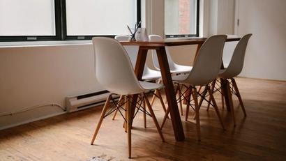 A room with a long table and six while chairs surrounding it