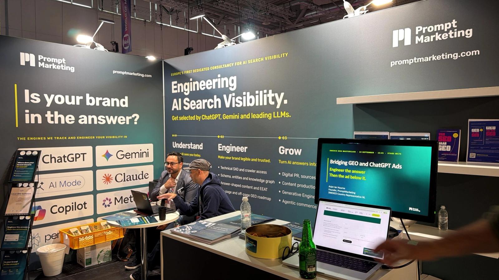 The PromptMarketing booth at DMEXCO 2026 with the message Engineering AI Search Visibility and a visitor in conversation.