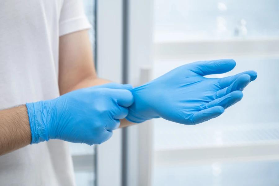 Nitrile Gloves are being put on in a clean and organized environment, likely a medical or laboratory setting.