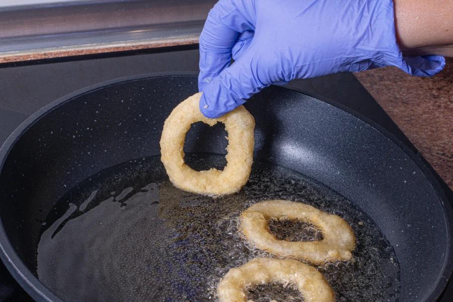 XL disposable gloves used in frying onion rings in a pan, ensuring hygiene and protection during cooking. 