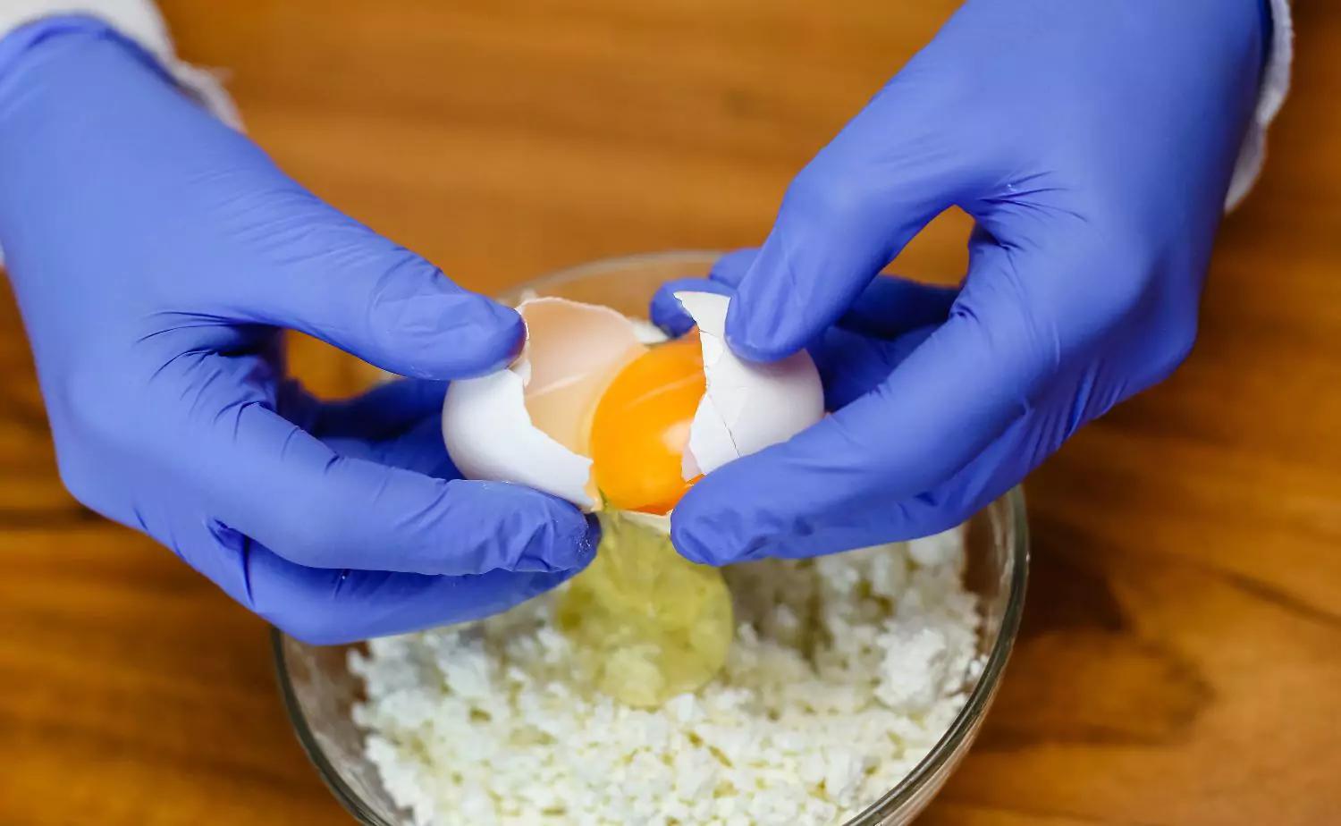 Nitrile Gloves being used to crack eggs into a bowl for cooking preparation